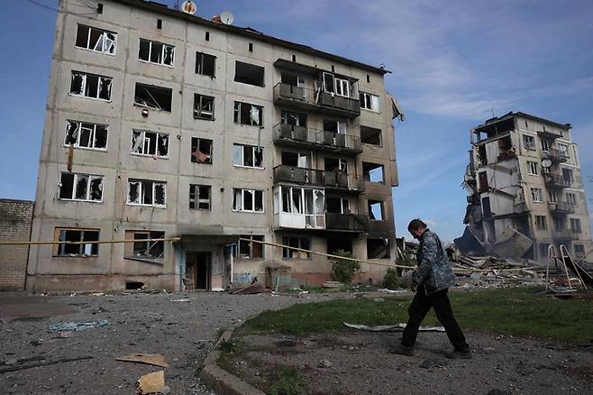 지난 15일(현지시간) 우크라이나 도네츠크주 오체레티네 마을 주민이 공중폭격으로 파괴된 건물 앞을  지나가고 있다. AFP연합뉴스