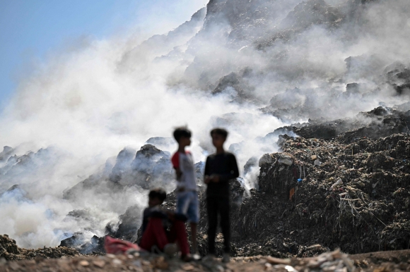 2024년 4월 21일 뉴델리의 가지푸르 매립지에서 발생한 화재로 인해 연기가 피어오르는 가운데, 거대한 ‘쓰레기장’에 서 있는 현지 소년들. 2024. 04. 22 AFP 연합뉴스