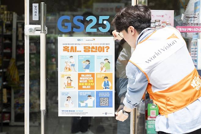 지난 23일 서울 영등포구 GS25 매장에 포스터를 부착하고 있는 월드비전 직원  [월드비전 제공]