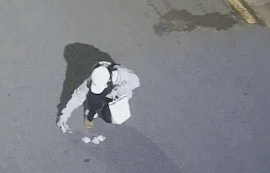 골목길에서 한 남성이 떨어뜨린 현금 뭉치를 줍는 B양의 모습.<경찰청 유튜브 캡처>