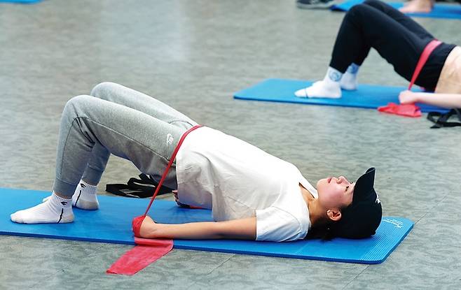 한 참가자가 매트에 누워 운동하고 있다.