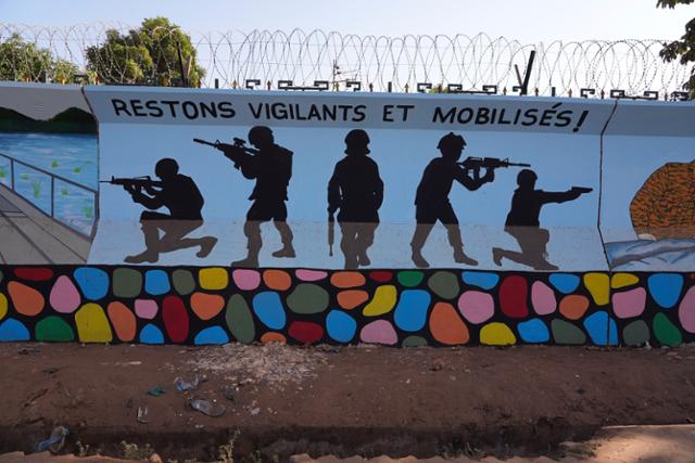 지난해 3월 1일 서아프리카 국가인 부르키나파소의 수도 와가두구 거리에 군인들의 총격을 묘사한 벽화가 그려져 있다. 국제인권단체 휴먼라이츠워치는 25일 공개한 보고서에서 "정부군이 마을 두 곳을 공격해 민간인 223명을 학살했다"고 밝혔다. 와가두구=AP 연합뉴스 자료사진