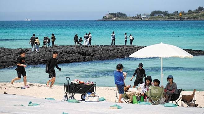 25일 오후 제주시 한림읍 협재해수욕장을 찾은 관광객들이 파라솔 아래 앉아 바닷바람을 쐬고 있다. /뉴시스