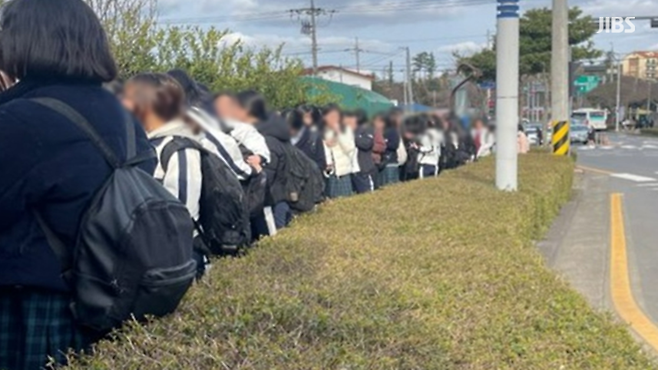 수업이 끝나고 버스를 타기 위해 긴 줄을 서서 기다리고 있는 학생들