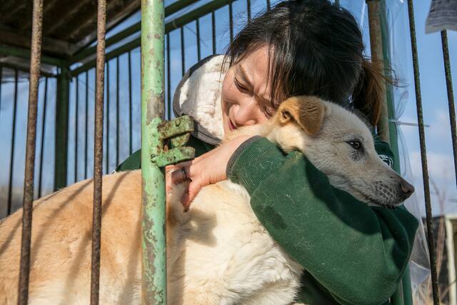 동물보호단체인 ‘한국 휴메인 소사이어티 인터내셔널’ 관계자가 한 개농장에서 개를 구출한 뒤 구출견을 안고 있다. 한국 휴메인 소사이어티 인터내셔널 제공