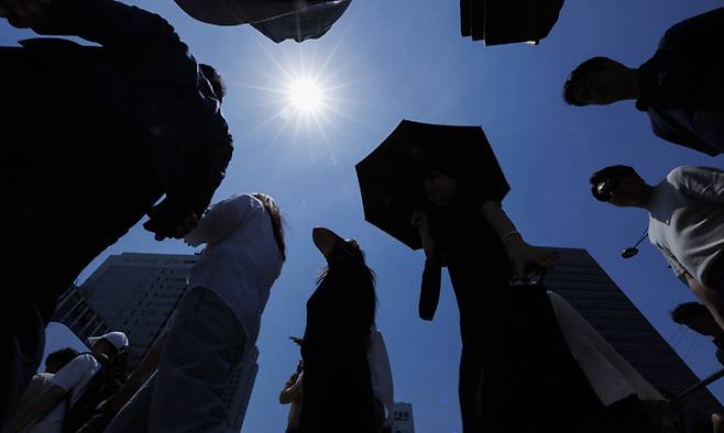 전국적으로 기온이 30도가 넘는 불볕더위가 계속될 것으로 예보된 12일 서울 종로구 광화문 건널목에서 시민들이 작열하는 태양 아래 이동하고 있다. 연합뉴스