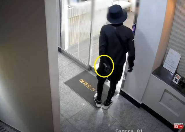 부산의 한 미용실을 찾은 남성이 왼손에 흉기를 들고 뒷짐을 지고 있는 모습. 한문철TV 캡처