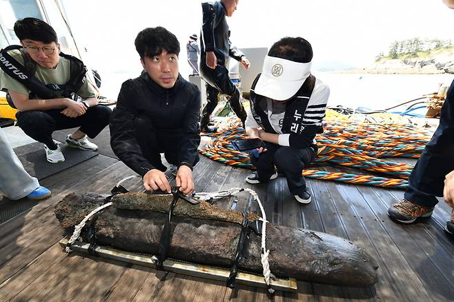 정헌 국립해양유물연구소 학예연구사가 26일 군산 선유도 해역에서 출수된 고려 시대 선박 부속구로 추정되는 1.5m 목재 끈을 풀고 있다. <국가유산청>