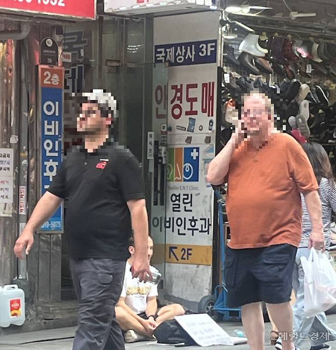 남대문 시장을 찾은 외국인 관광객들 사이로 자리에 앉아 구걸행위를 하고 있는 바딤의 모습이 보인다. 김민지 기자.