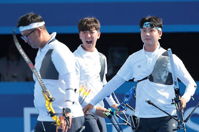 한국 남자 양궁 대표팀 김제덕(가운데)이 김우진에게 기합을 전하고 있다