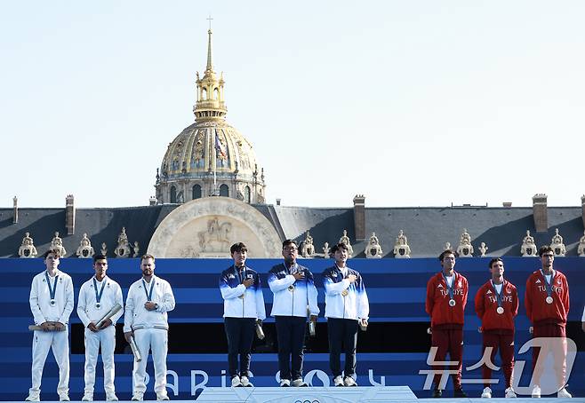 대한민국 양궁대표팀 김우진, 김제덕, 이우석이 30일(한국시간) 프랑스 파리 앵발리드에서 열린 2024 파리올림픽 양궁 남자 단체전 결승 시상식에서 애국가가 울려퍼질때 국민의례를 하고 있다. 2024.7.30/뉴스1