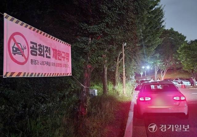 지난 12일 오후 7시30분께 성남시 분당구의 한 공원 노상주차장. 공회전 제한구역임을 알리는 현수막이 설치돼 있지만 일부 차량들이 장시간 시동을 틀고 정차해 있다. 한준호기자