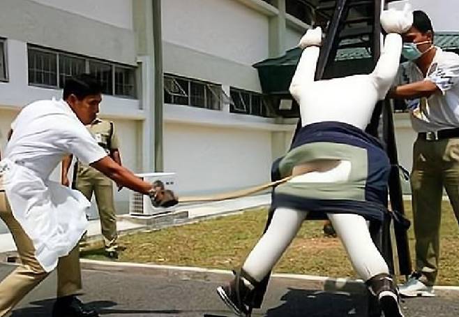 간수가 인형을 묶어 놓고 태형 시범을 보이고 있다. /Tamil Micset