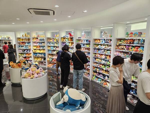 - 인형 진열대 앞에서 고민 중인 사람들