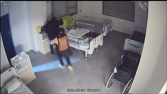 공주시 ㄴ요양원에서 입소한 지 하루밖에 지나지 않은 89살 민아무개씨가 두 손이 묶여 있는 동안 같은 방 노인 김아무개(82)씨에게 폭행을 당하자 뒤늦게 요양보호사가 황급히 다가가고 있다. 시시티브이 갈무리