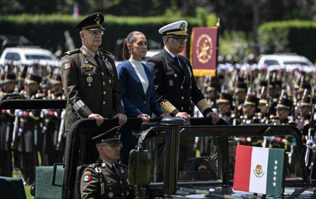 멕시코 개헌 200년 만에 첫 여성대통령으로 당선된 클라우디아 셰인바움 대통령(가운데)이 3일 멕시코 시티 캄포 마르테에서 열린 군 최고 사령관 취임식에 참석해 리카르도 트레비야 멕시코 국방장관(왼쪽), 레이문도 페드로 모랄레스 해군 장관(오른쪽)과 함께 의장대 사열을 받고 있다. 멕시코 시티=AFP 연합뉴스