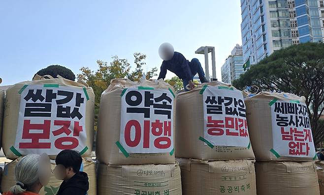 전국농민회총연맹(이하 ‘전농’)과 전국쌀생산자협회가 24일 오후 서울 농협중앙회 본관 앞에서 기자회견을 열고 나락값 7만원 공약 이행 등 즉각적인 쌀값 안정화 대책 마련을 촉구하는 가운데 관계자들이 나락포대에 항의 문구를 붙이고 있다.