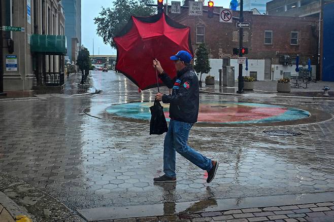 허리케인 밀턴이 접근하고 있던 9일 플로리다주 올랜도 시내에서 한 남자가 우산을 들고 있다. / AFP 연합뉴스