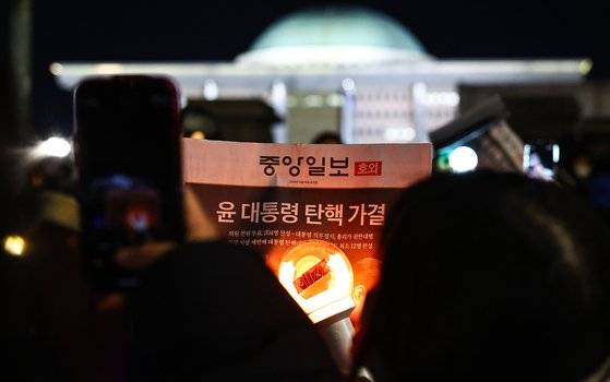 윤석열 대통령 탄핵안이 국회에서 가결된 14일 서울 여의도 일대에서 시민들이 중앙일보 호외를 들고 기념사진을 찍고 있다. 김종호 기자