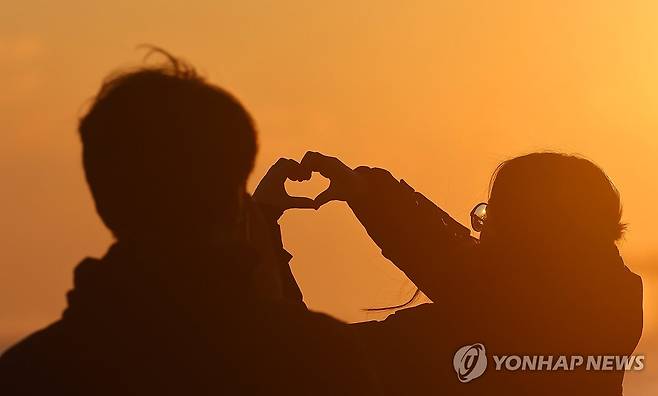 정동진에서 맺은 사랑의 다짐 (강릉=연합뉴스) 유형재 기자 = 2025년 새해를 열흘가량 앞둔 22일 해맞이 명소인 강원 강릉시 정동진 앞바다에서 연인이 손으로 하트를 만들며 사랑을 약속하고 있다. 2024.12.22 yoo21@yna.co.kr