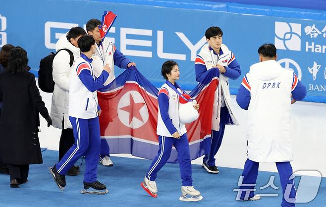 북한 렴대옥·한금철이 12일 중국 헤이룽장성 하얼빈 빙상훈련센터 다목적홀에서 열린 시상식을 마치고 인공기를 펼치고 있다. /사진=뉴스1