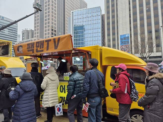 15일 서울 종로구 광화문 일대에서 열린 윤석열 대통령 탄핵반대 집회에서 참석자들이 푸드트럭에서 음식을 받기 위해 줄을 서있다. 사진=장유하 기자