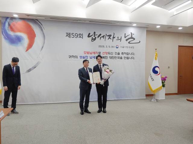 박태진(오른쪽) 대진반도체 사장이 제59회 납세자의 날 행사에서 모범납세자로 선정된 뒤 정재수(왼쪽) 서울지방국세청장과 기념 촬영을 하고 있다. <대진반도체 제공>