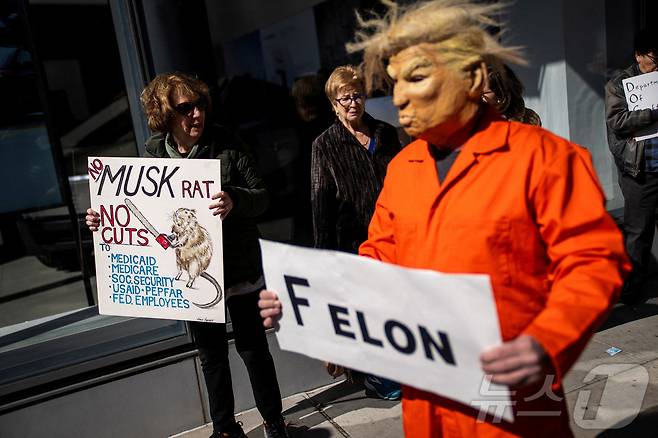 도널드 트럼프 미국 대통령 마스크를 쓴 남자가 2025년 3월 1일 미국 뉴욕시에서 테슬라 매장 밖에서 시위에 참여하고 있다. ⓒ 로이터=뉴스1