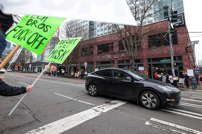 2월15일(현지시간) 미국 워싱턴 시애틀에 있는 테슬라 쇼룸 앞에서 일론 머스크 테슬라 최고경영자(CEO)가 이끄는 정부효율부(DOGE) 정책에 반대하는 시위가 열리고 있다. /AFPBBNews=뉴스1