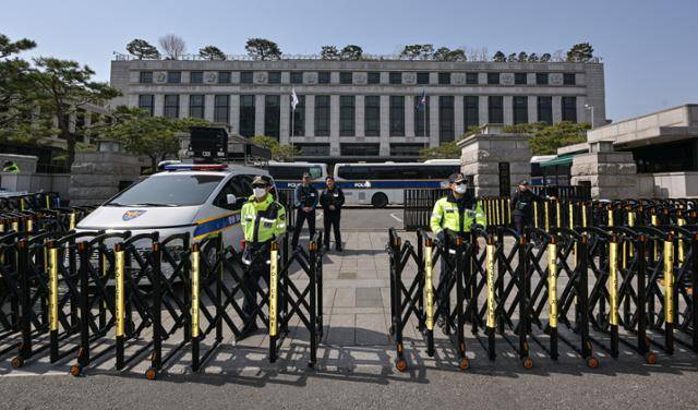윤석열 대통령 탄핵심판 선고가 임박한 가운데 14일 서울 종로구 헌법재판소 정문에서 경찰이 삼엄한 경계 태세를 갖추고 있다. 사진 속 헌재 본관 건물 상단에 모양과 크기가 같은 무궁화 아홉 송이가 새겨져 있다. 하상윤 기자