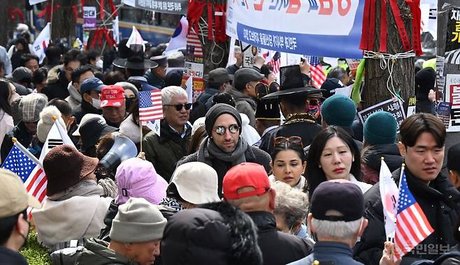 윤석열 대통령의 탄핵 심판 선고를 앞둔 17일 서울 종로구 헌법재판소 앞 인근에서 외국인 관광객들이 윤 대통령 지지자들 사이로 지나가고 있다.