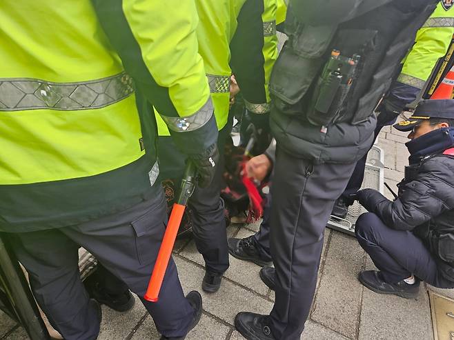 20일 오전 서울 종로구 헌법재판소 인근에서 한 시위자가 경찰의 강제 해산 조치에 항의하며 바닥에 누워 저항하고 있다. /장윤 기자