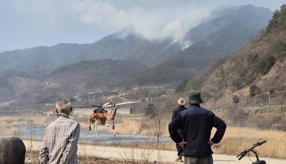22일 오후 경남 산청군의 한 마을 주민들이 강 건너편에서 다시 확산 중인 산불을 보며 우려하고 있다. 안대훈 기자