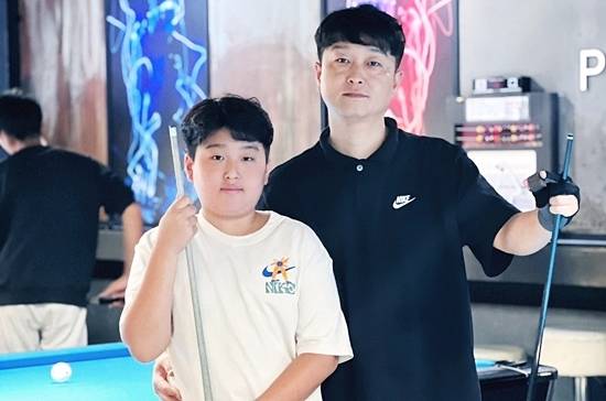 올해 14세 ‘포켓볼 유망주’ 김민준(익산 부송중 2)이 전국당구대회 성인부에서 쟁쟁한 선수들을 제치고 최연소 8강에 진출했다. 포켓볼 선수인 아버지 김택균 씨와 포즈를 취한 김민준. (사진=김택균)