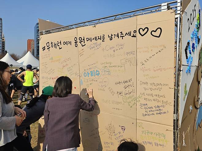 23일 오전 서울 여의도 한강공원에서 열린 ‘2025 무해런’에서 참가자들이 한켠에 마련된 종이박스에 대회 응원 메시지를 남기고 있다. 김광우 기자.