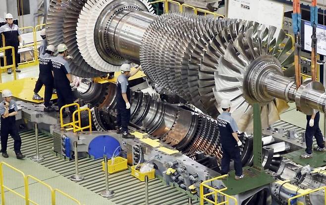 두산에너빌리티 직원들이 가스터빈 초도호기 최종 조립을 위해 로터 블레이드를 케이싱에 설치하고 있다. /두산에너빌리티 제공