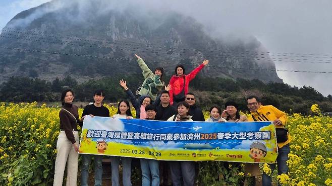 산방산 유채꽃밭을 배경으로 대만 여행업계 팸투어단이 기념촬영을 하고 있다. (제주관광공사 제공)