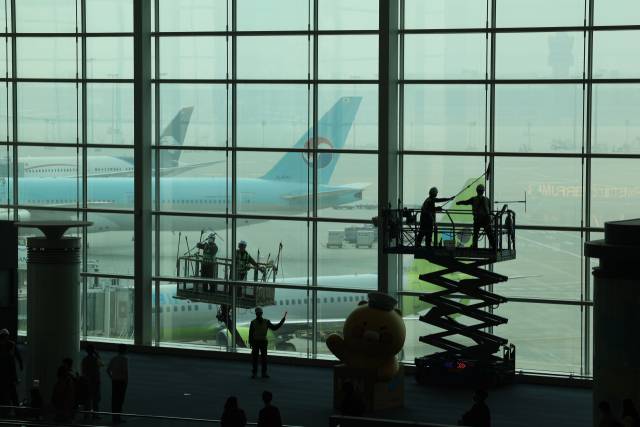 25일 인천국제공항 제2여객터미널에서 인천공항운영서비스 환경미화원들이 공항터미널 외부 유리 벽 물청소를 하고 있다. 연합뉴스