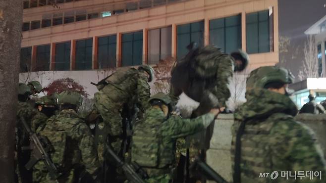 4일 오전0시 50분쯤 군병력이 서울 여의도 국회의사당 담장을 넘어 경내로 진입하고 있다./사진=이찬종 기자