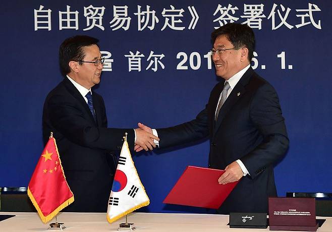 2015년 6월 서울의 한 호텔에서 열린 '한·중 자유무역협정 서명식'에서 윤상직 산업통상자원부 장관(오른쪽)이 가오후청 중국 상무부장(왼쪽)과 악수를 나누고 있다