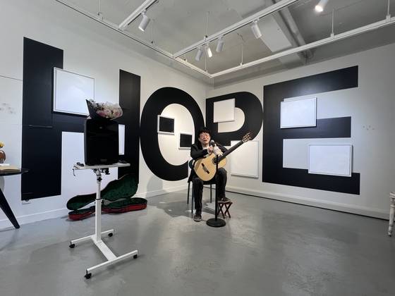 전시장에서 아트토크 중인 김창완. HOPE라고 쓴 벽면 위 그림들이 최신작이다.