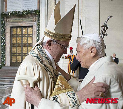 프란치스코 교황(왼쪽)이 8일 카톨릭 '자비의 희년' 개막을 앞두고 명예교황 베네딕토 16세와 포옹하고 있다. 교황은 뒤편에 보이는 청동 '성문'을 열어 1년 계속될 자비행의 시작을 알린다. 2015. 12. 8./AP=뉴시스