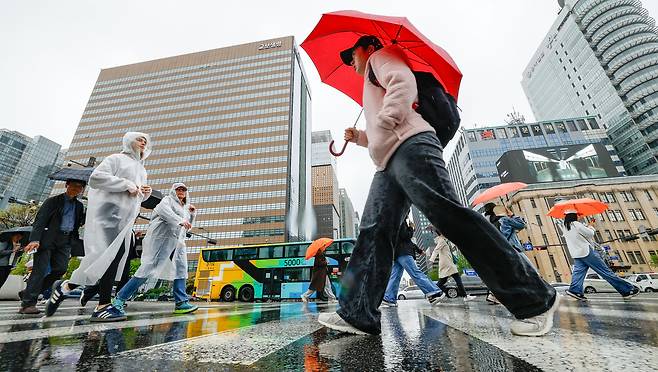 서울, 인천, 경기 등에 10~50㎜의 많은 비가 예보된 22일 서울 종로구 광화문광장에서 시민과 관광객들이 우산을 쓴 채 길을 건너고 있다.