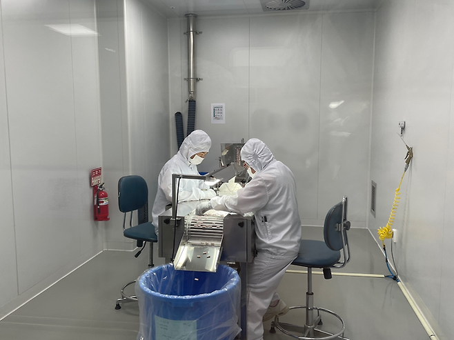 알피바이오 작업자가 제조된 캡슐 알약을 선별하고 있다. 진동으로 고르게 분포된 캡슐의 이상 유무를 검수한 후 포장 공정에 투입된다. 포장이 된 제품은 비전선별기로 한 번 더 불량품 여부를 확인한다.