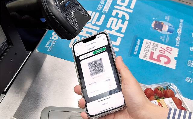 기자가 예금 토큰 전자지갑 큐알(QR)코드로 물건을 구매하고 있다.