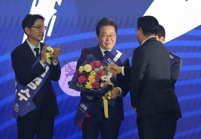 27일 경기도 고양시 킨텍스에서 열린 제21대 대통령 선거 후보자 선출을 위한 수도권·강원·제주 합동연설회에서 이재명 후보가 대선후보로 선출된 후 박찬대 더불어민주당 대표 직무대행 겸 원내대표로부터 꽃다발을 받고 악수하고 있다. 2025.04.27. 뉴시스