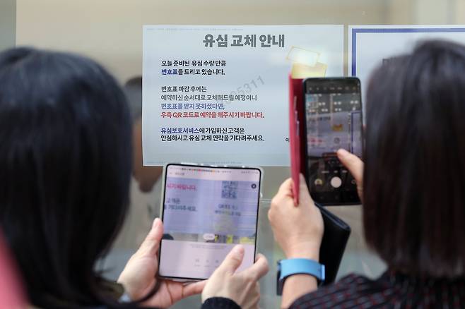 SK텔레콤이 가입자 유심 무상 교체를 시작한 28일 오전 서울 종로구 T월드 직영매장 앞에서 번호표를 받지 못한 고객들이 온라인 예약을 하고 있다./뉴스1