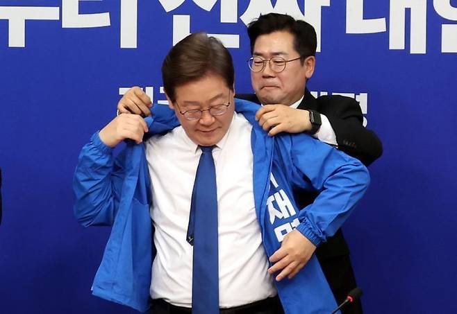 박찬대 더불어민주당 대표직무대행 겸 원내대표가 28일 오전 국회에서 열린 최고위원회의에서 이재명 민주당 21대 대선 후보의 선거운동복을 입혀주고 있다. ⓒ뉴시스