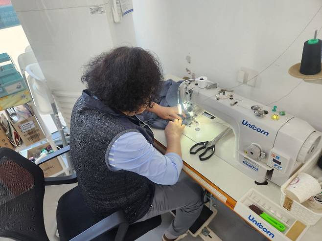 28일 구멍난 노동자 작업복을 재봉틀로 꿰매는 모습 (사진=정바름 기자)