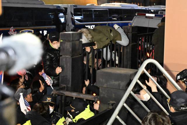 1월 19일 윤석열 전 대통령 구속영장 발부에 반발한 지지자들이 서울서부지방법원 진입을 위해 담장을 넘고 있다. 연합뉴스